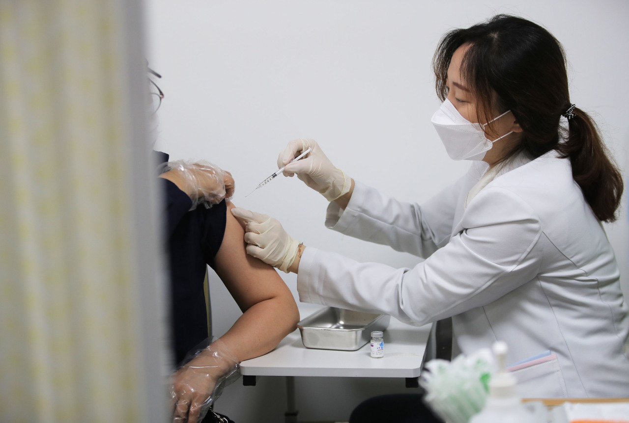 A health care worker administers an AstraZeneca shot to a citizen at a clinic in Seoul on Friday. (Yonhap)