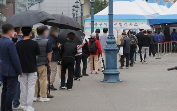 People stand in line to receive coronavirus tests at a makeshift clinic in front of Seoul Station on Thursday. (Yonhap)