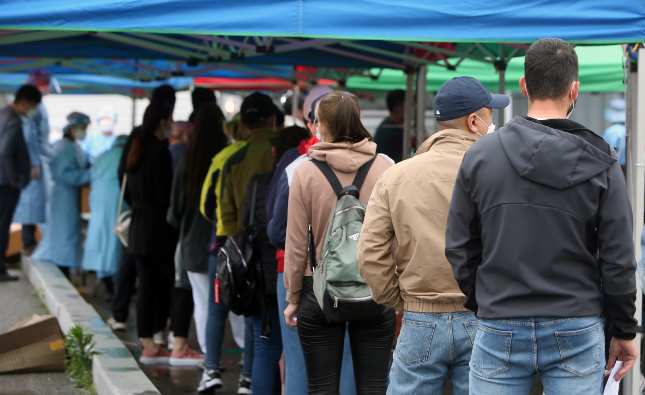 People stand in line in the rain to take coronavirus tests at a makeshift clinic in front of Seoul Station on Friday. (Yonhap)