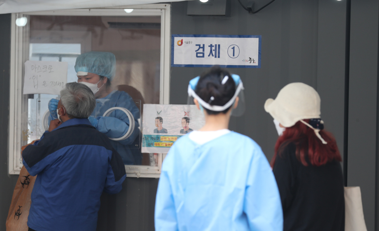 A medical worker carries out COVID-19 tests at a makeshift clinic in central Seoul on Sunday. (Yonhap)