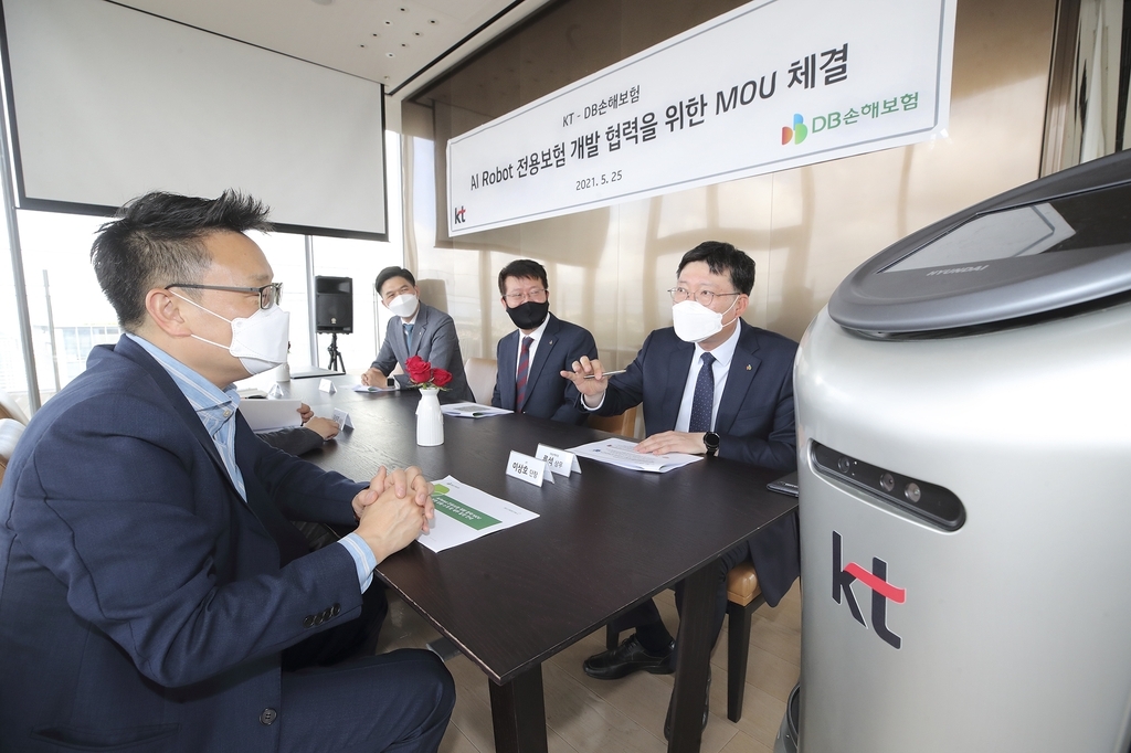 In this photo provided by KT Corp. on Wednesday, Lee Sang-ho (L), head of KT's AI robot business, speaks with officials from DB Insurance Co. for the development of insurance programs for service robots at KT's office building in Seoul. (KT Corp.)