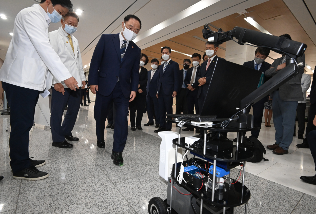 Finance Minister Hong Nam-ki looks at a walking assist robot for Parkinson's disease patients at Seoul National University’s Medical Research Center for Innovation in Seoul, Wednesday. (Yonhap)
