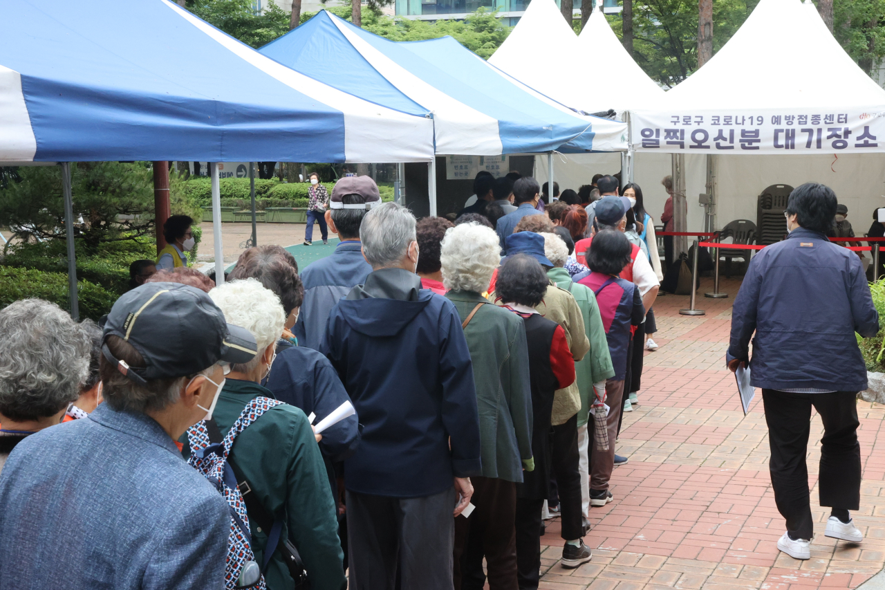 Elderly people stand in single file to receive COVID-19 vaccines at a public health facility in Seoul, Monday. (Yonhap)