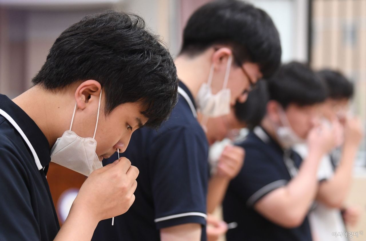 Students at Seoul Robotics High School in southern Seoul collect specimens from their noses using COVID-19 self-testing kits on Thursday. (Yonhap)