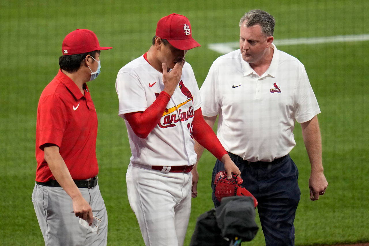 In this Associated Press photo, St. Louis Cardinals' starter Kim Kwang-hyun (C) walks off the field with trainer Chris Conroy (R) and interpreter Craig Choi before the start of the top of the fourth inning of a Major League Baseball regular season game against the Cincinnati Reds at Busch Stadium in St. Louis on Friday. (AP-Yonhap)