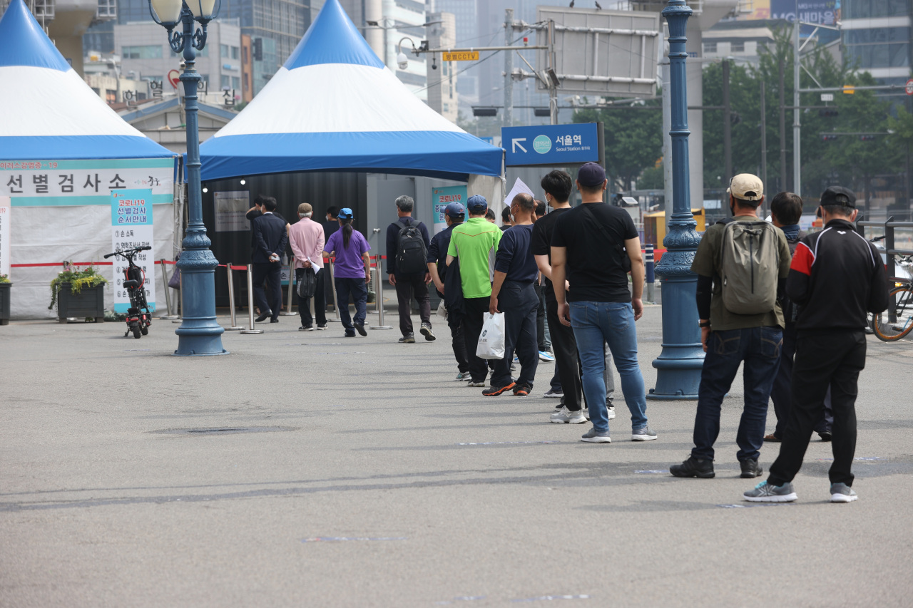 Citizens wait in line to receive virus tests at a makeshift virus clinic in Seoul on Sunday. (Yonhap)