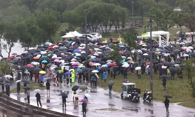 Mourners stand with umbrellas to commemorate the death of Sohn Jung-min in Banpo Han River Park in Seoul in May. (Yonhap)