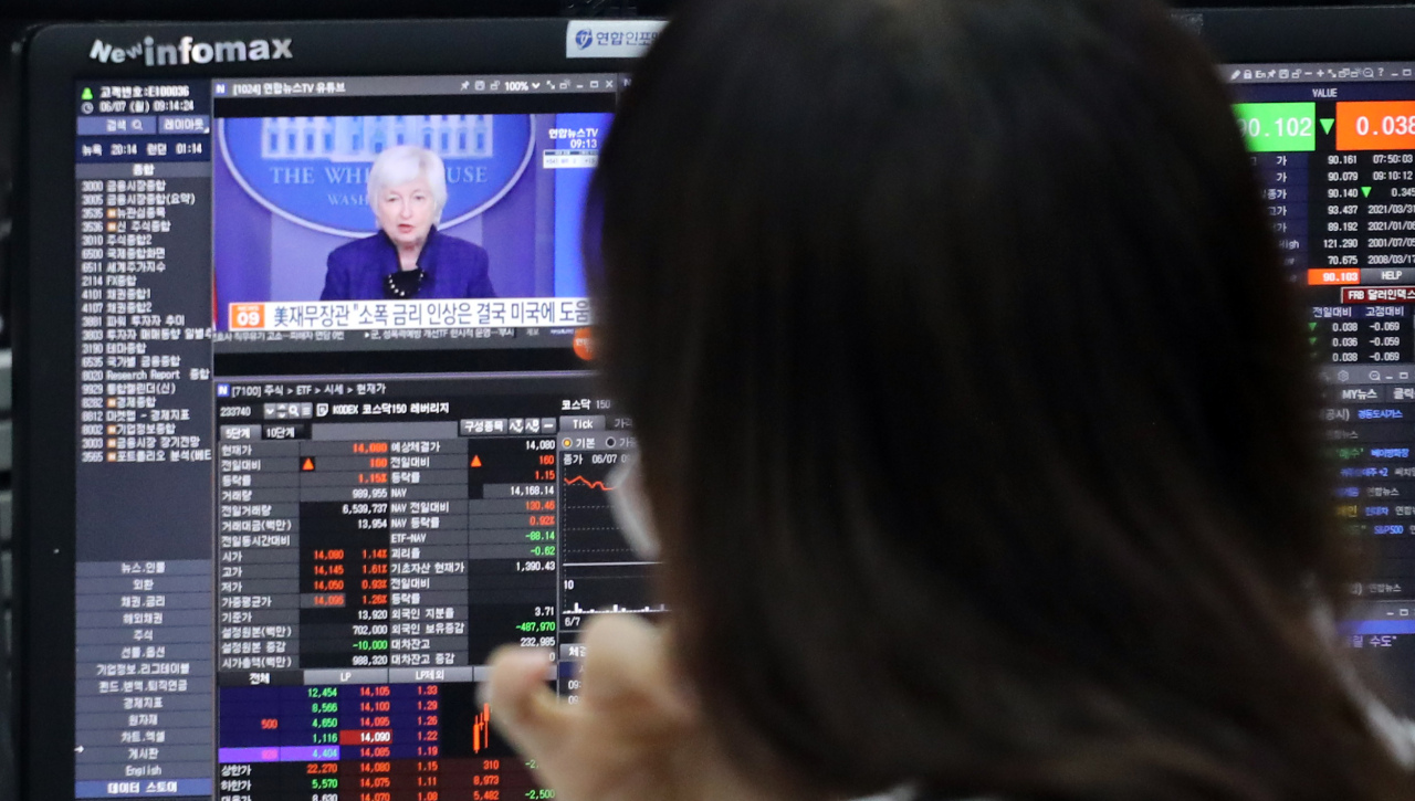 Staff at Hana Bank‘s dealing room in Seoul watch TV reports on market prospects over the US Fed’s interest rate hike Monday. (Yonhap)