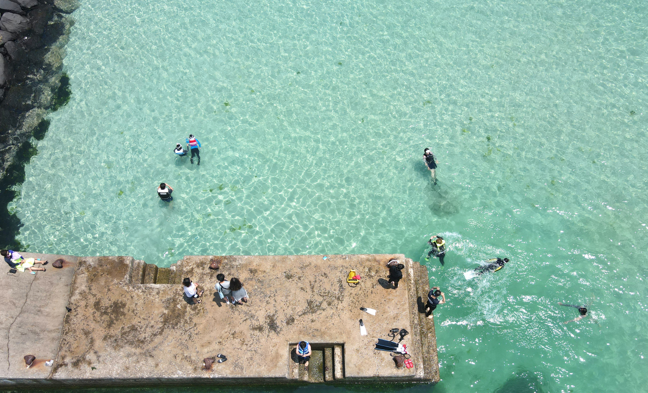 Tourists snorkle in the water in early summer weather in Jeju on Monday. (Yonhap)