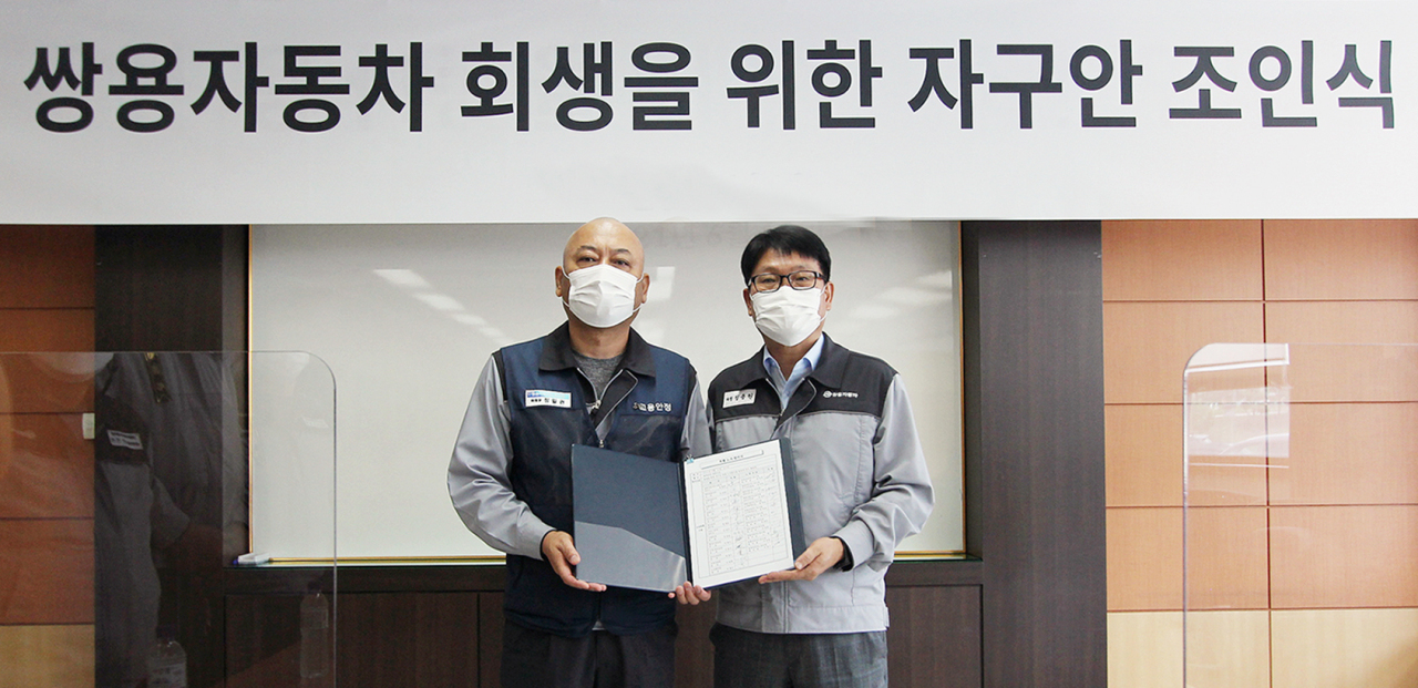 SsangYong Motor Co.'s labor union chief Jung Il-kwon (L) and court-appointed manager Chung Yong-won pose for a photo after signing an agreement on self-help measures for the financially troubled automaker at its Pyeongtaek factory, 70 kilometers south of Seoul, on Monday in this photo provided by SsangYong. (SsangYong Motor)