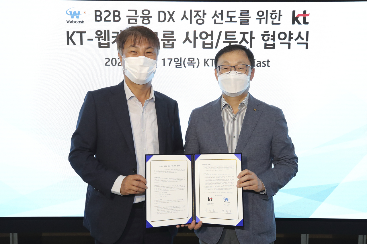 KT CEO Ku Hyeon-mo (right) holds up an agreement with WebCash Group Chairman Seok Chang-gyu at KT's headquarters in central Seoul on Thursday. (KT)