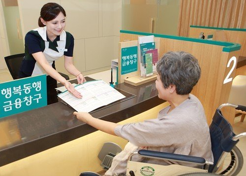A senior citizen talks with a bank clerk at Hana Bank’s branch in central Seoul. (Hana Bank)