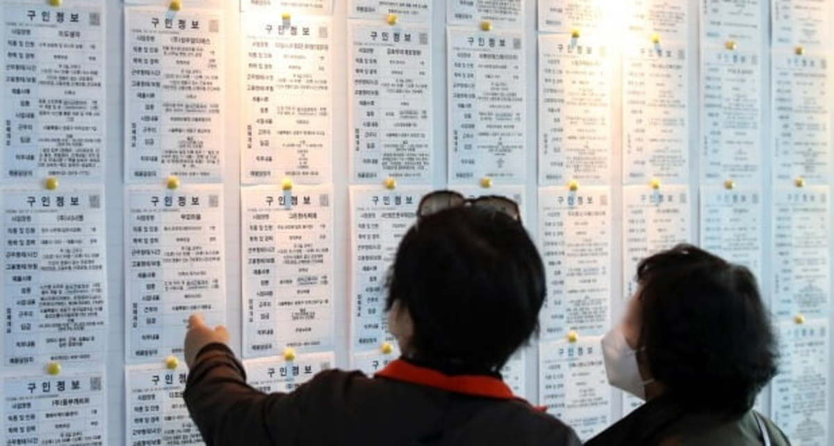 Two women look at a billboard advertising jobs. (Yonhap)