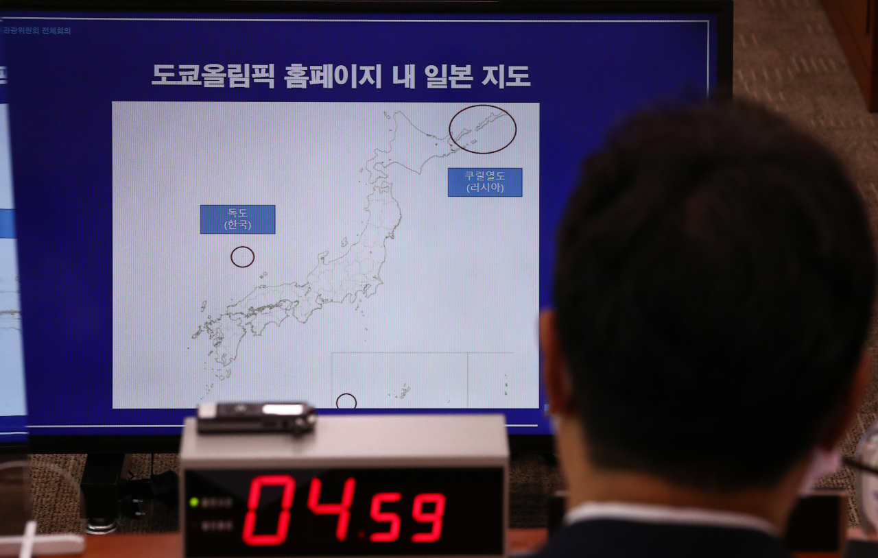 South Korea's Culture, Sports and Tourism Minister Hwang Hee (in foreground) observes a map of the Tokyo Olympics torch relay route that includes the East Sea islets of Dokdo as Japanese territory during a parliamentary committee meeting at the National Assembly in Seoul last Monday. (Yonhap)