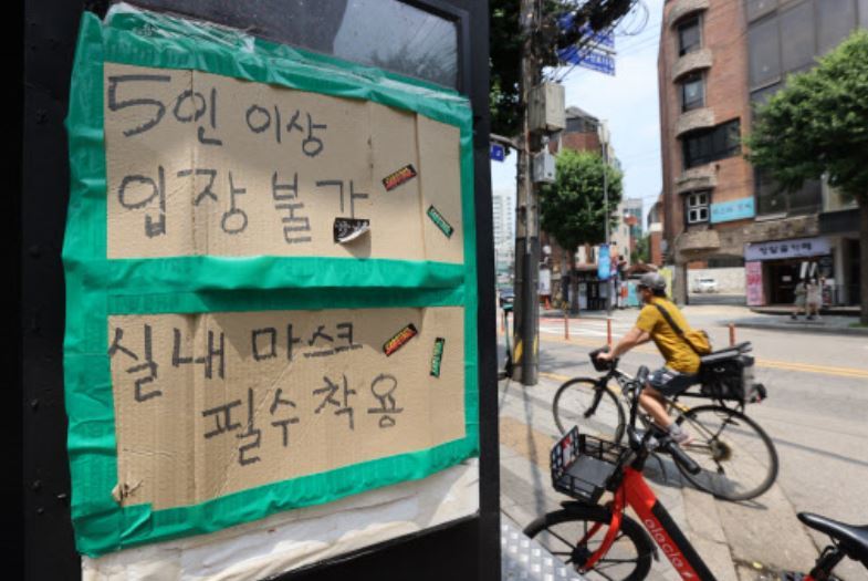 This photo taken on June 20, 2021, shows a sign posted near the entrance of a bar in Seoul to inform customers that private gatherings of five or more people are not allowed under the current social distancing rules amid the coronavirus pandemic. (Yonhap)