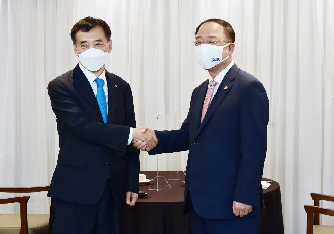 Finance Minister and Deputy Prime Minister Hong Nam-ki, right, shakes hands with Bank of Korea Gov. Lee Ju-yeol after a breakfast meeting at the Korea Press Center headquarters in central Seoul on Friday. (Yonhap)