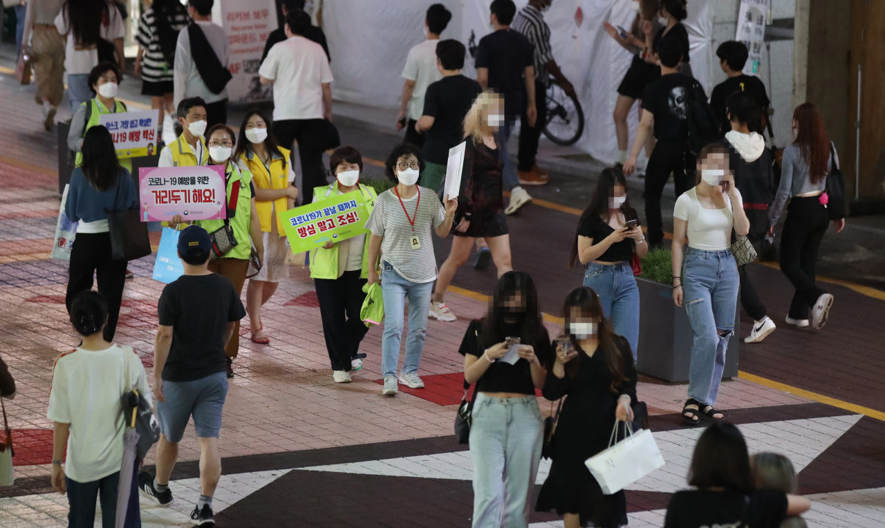 Officials at Mapo-gu ward office conduct a street campaign in Seoul on Friday, to encourage people to keep a distance from one another and wear masks amid a sharp spike in new COVID-19 cases. (Yonhap)