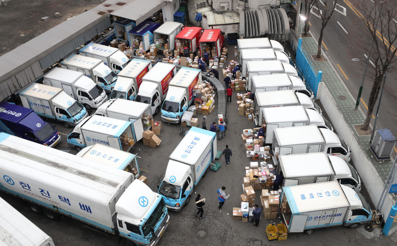 Delivery workers load parcels onto trucks. (Yonhap)
