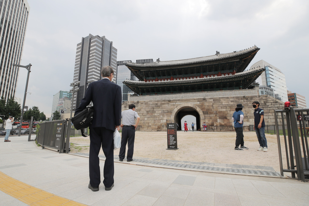 Pedestrians stand in front of the city gate Sungnyemun in central Seoul. (Yonhap)
