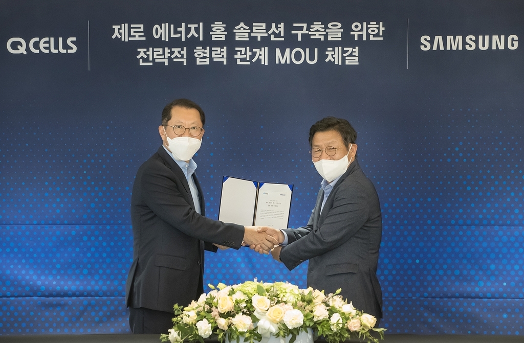 This photo provided by Samsung Electronics Co. on Monday, shows Lee Jae-seung (R), head of Samsung's consumer electronics business, posing for a photo with Hanwha Q Cells CEO Kim Hee-chul after signing a cooperation agreement for home energy solutions in Seoul. (Samsung Electronics Co.)