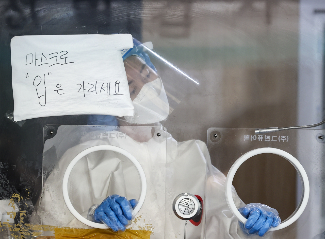 A medical worker is in preparation for a COVID-19 test in Seoul on Sunday. (Yonhap)