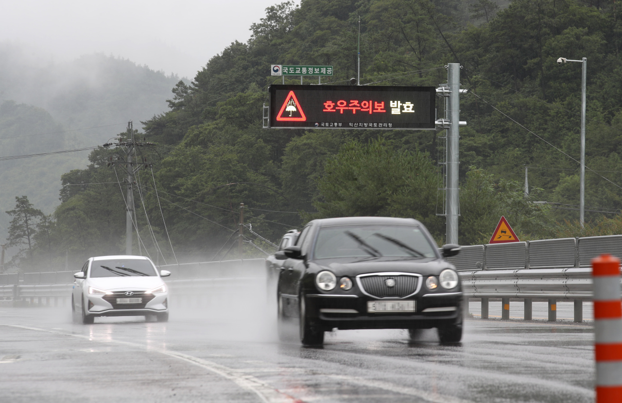 Cars run on a rain-soaked expressway in Boseong, southwestern South Korea, on Monday, with an electronic signage publicizing a heavy rain advisory. (Yonhap)