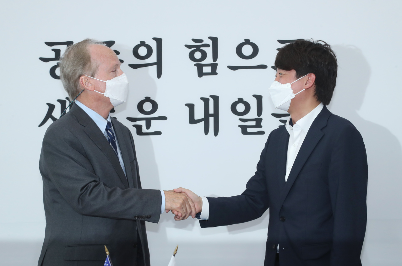 Lee Jun-seok, the chief of the main opposition People Power Party (R), and acting US Ambassador to South Korea Robert Rapson shake hands during their meeting at the National Assembly in Seoul on Tuesday. (Yonhap)