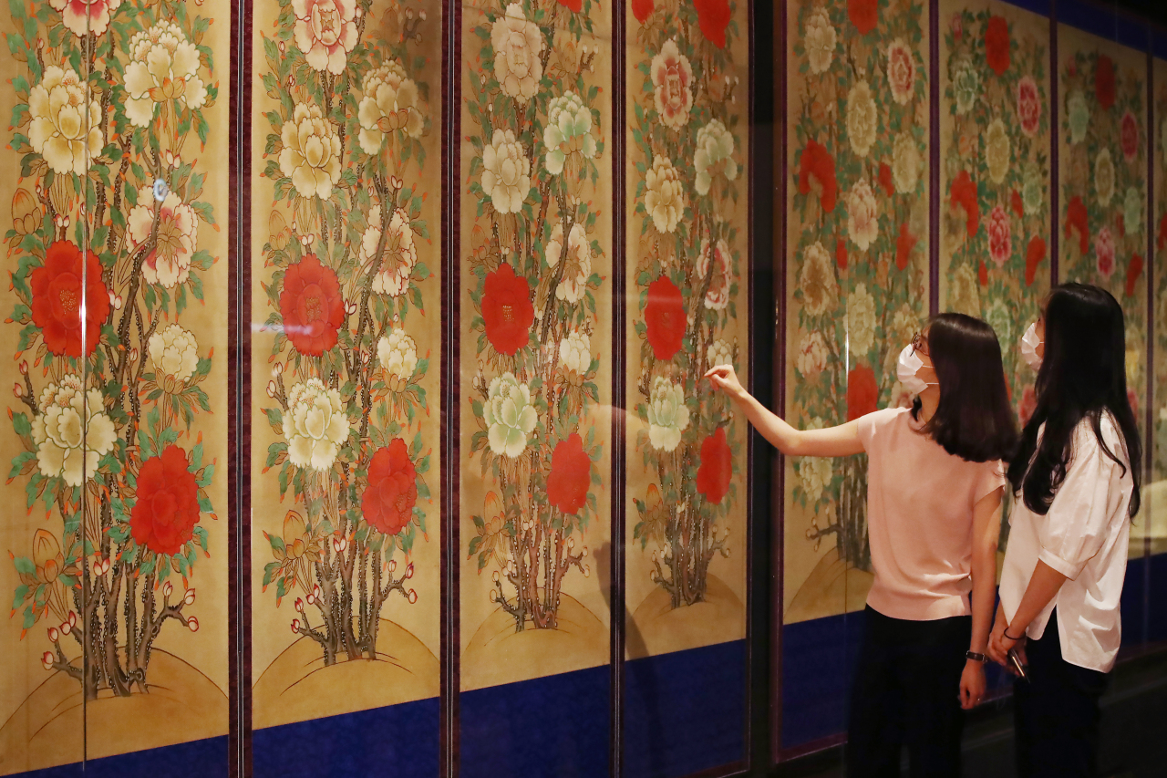 Visitors look at huge folding screens decorated with peonies that were used for funerals. (Yonhap)