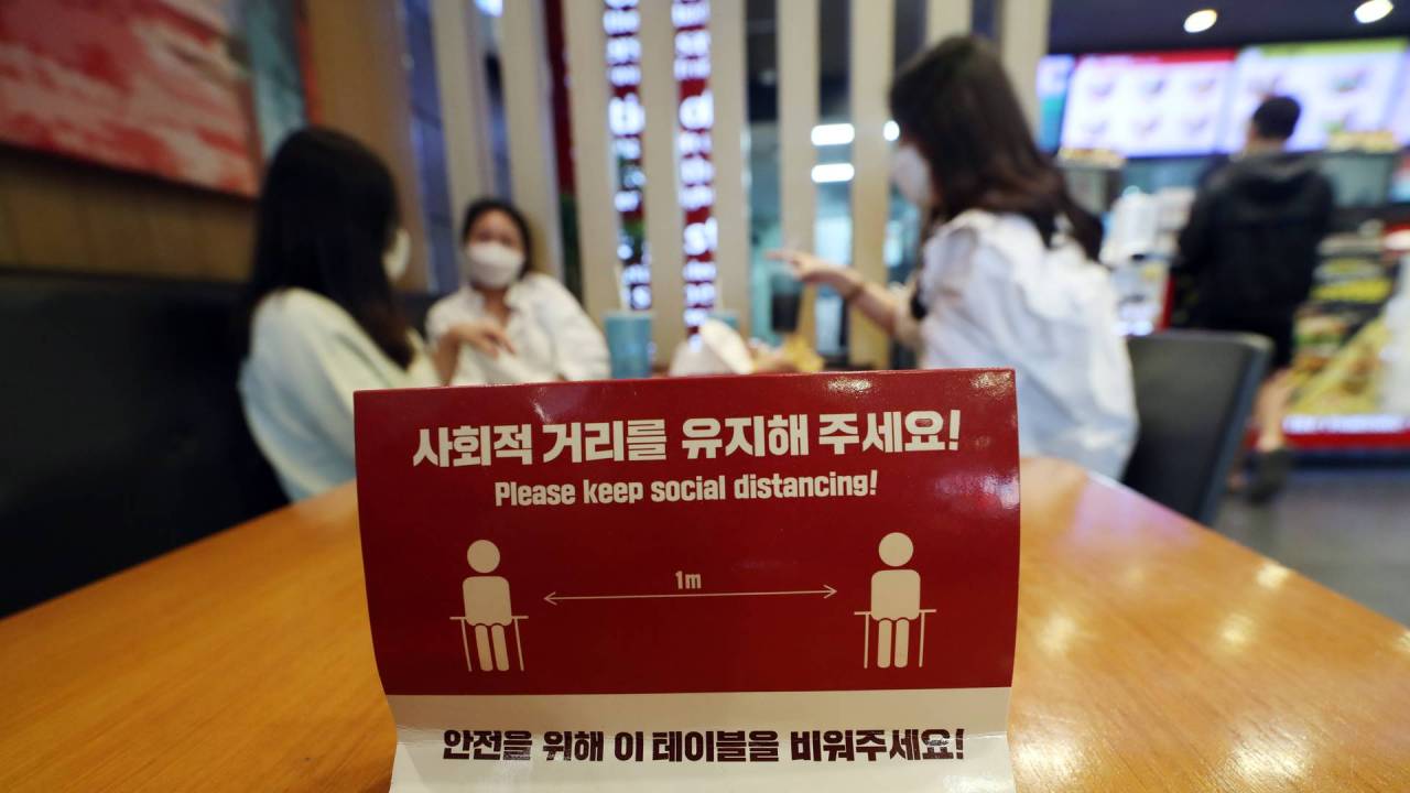 This photo from Yonhap News TV shows social distancing rule guidance and customers at a cafe in Seoul. (Yonhap)