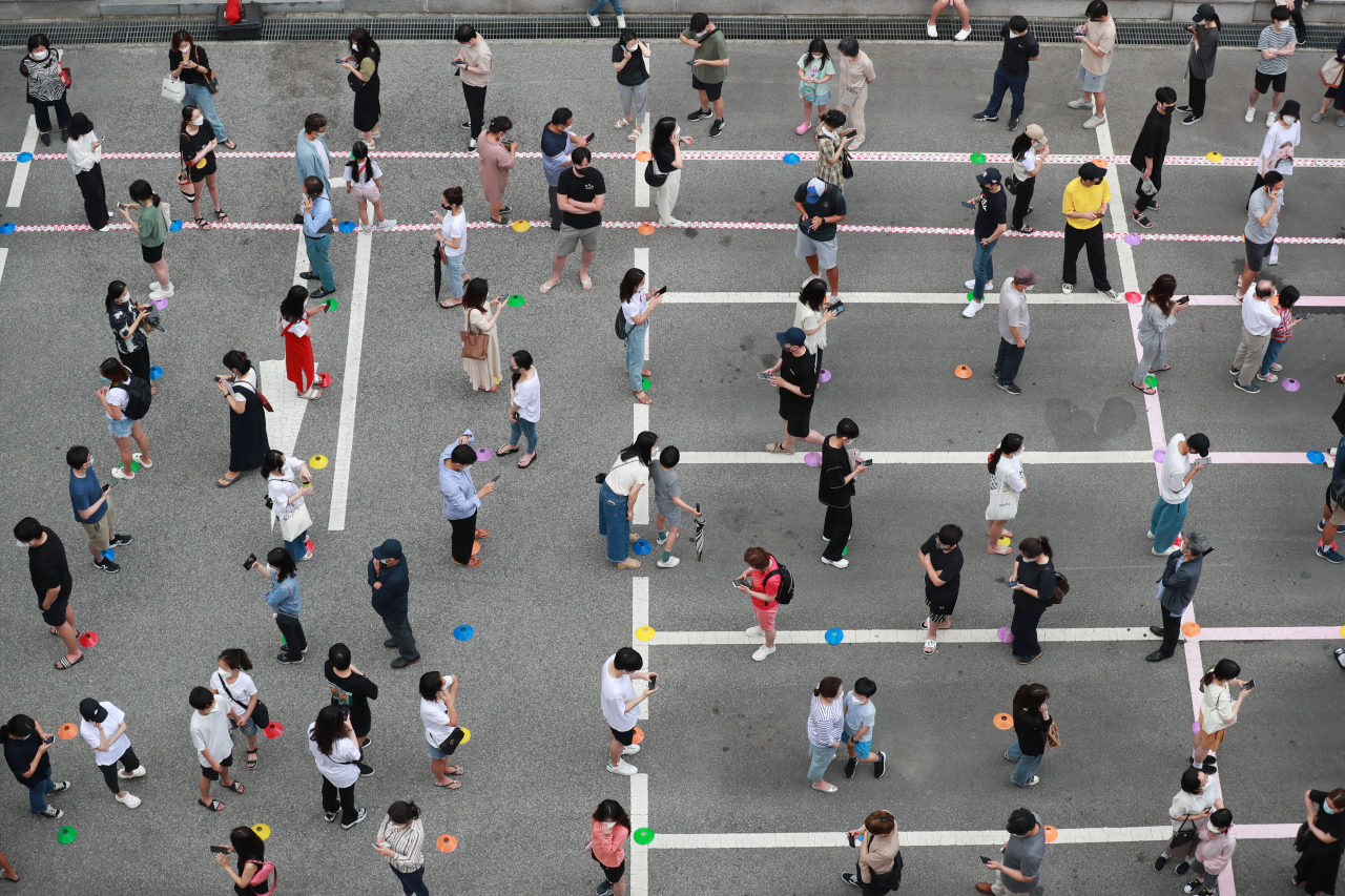 Citizens stand in line to take tests at a COVID-19 testing station in Seoul on Friday, when the country reported a record daily high of 1,316 new infections, including 80 from abroad. (Yonhap)