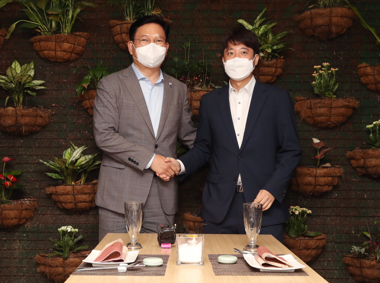 Song Young-gil (left), chairman of the ruling Democratic Party (DP), and Lee Jun-seok, chairman of the main opposition People Power Party (PPP), pose for photos at a dinner meeting held at a restaurant in Yeouido, western Seoul on Monday. (Yonhap)