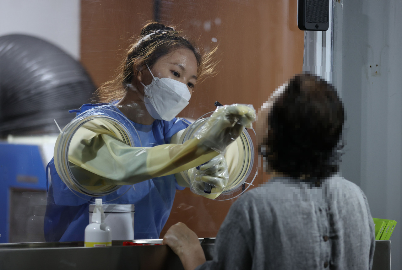 A medical worker carries out COVID-19 tests at a makeshift clinic in western Seoul on Monday. (Yonhap)