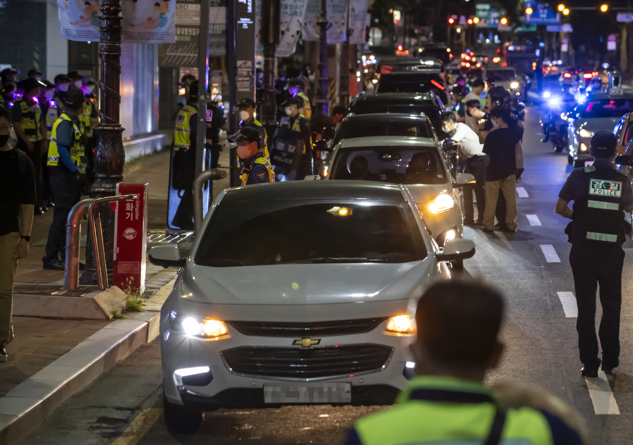 Small-business owners stage a drive-through rally early Thursday morning in Jung-gu, central Seoul, and flash their car’s hazard lights in protest of strict social distancing rules and a lack of support measures from the government. (Yonhap)
