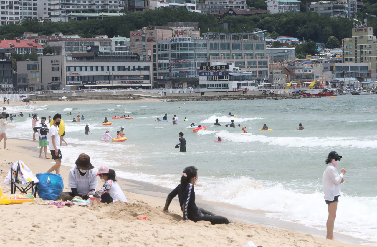 People swim and relax at Haeundae Beach in Busan on Saturday. (Yonhap)