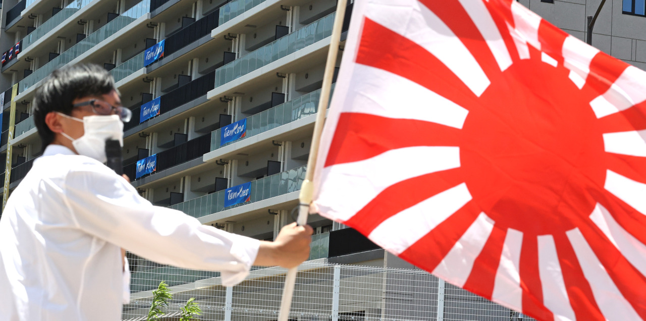 A member of the far-right National Party of Japan waves the Rising Sun Flag outside the Olympic athletes' village in Tokyo on Friday, in protest to a message hung outside South Korean athletes' rooms that some Japanese accuse of being overly political and anti-Japanese. (Yonhap)