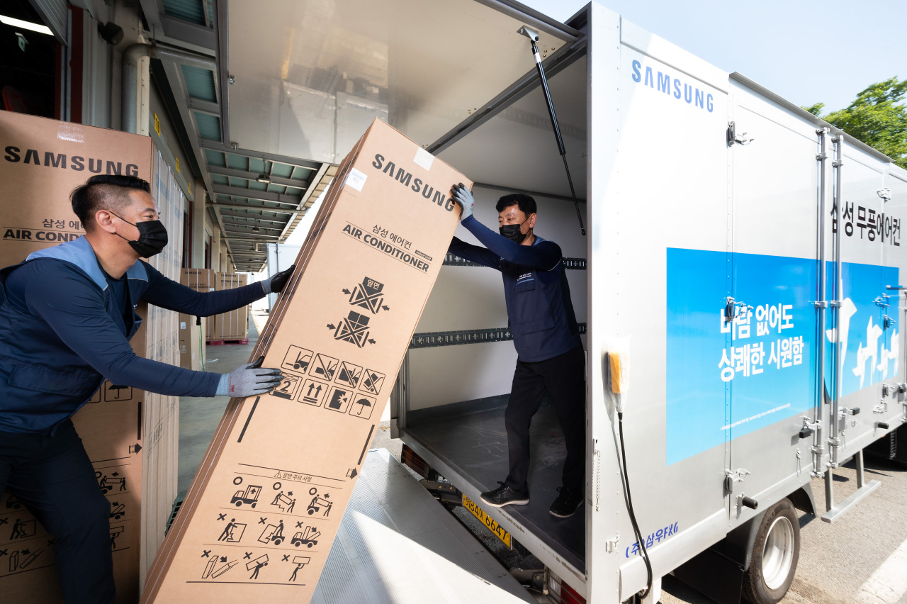 This photo provided by Samsung Electronics Co. on Friday, shows two of the company's logistics workers shipping air conditioners at its warehouse in Suwon, 46 kilometers south of Seoul. (Samsung Electronics Co.)