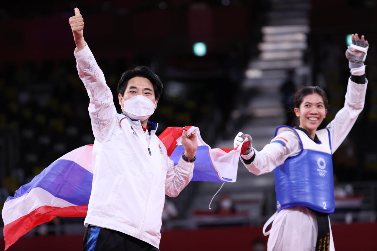 Choi Young-seok (L), the South Korean-born coach of the Thai taekwondo team, and his athlete Panipak Wongpattanakit celebrate Wongpattanakit's gold medal in the women's 49kg class at the Tokyo Olympics at Makuhari Messe Hall A in Chiba, Japan, on Saturday. (Yonhap)