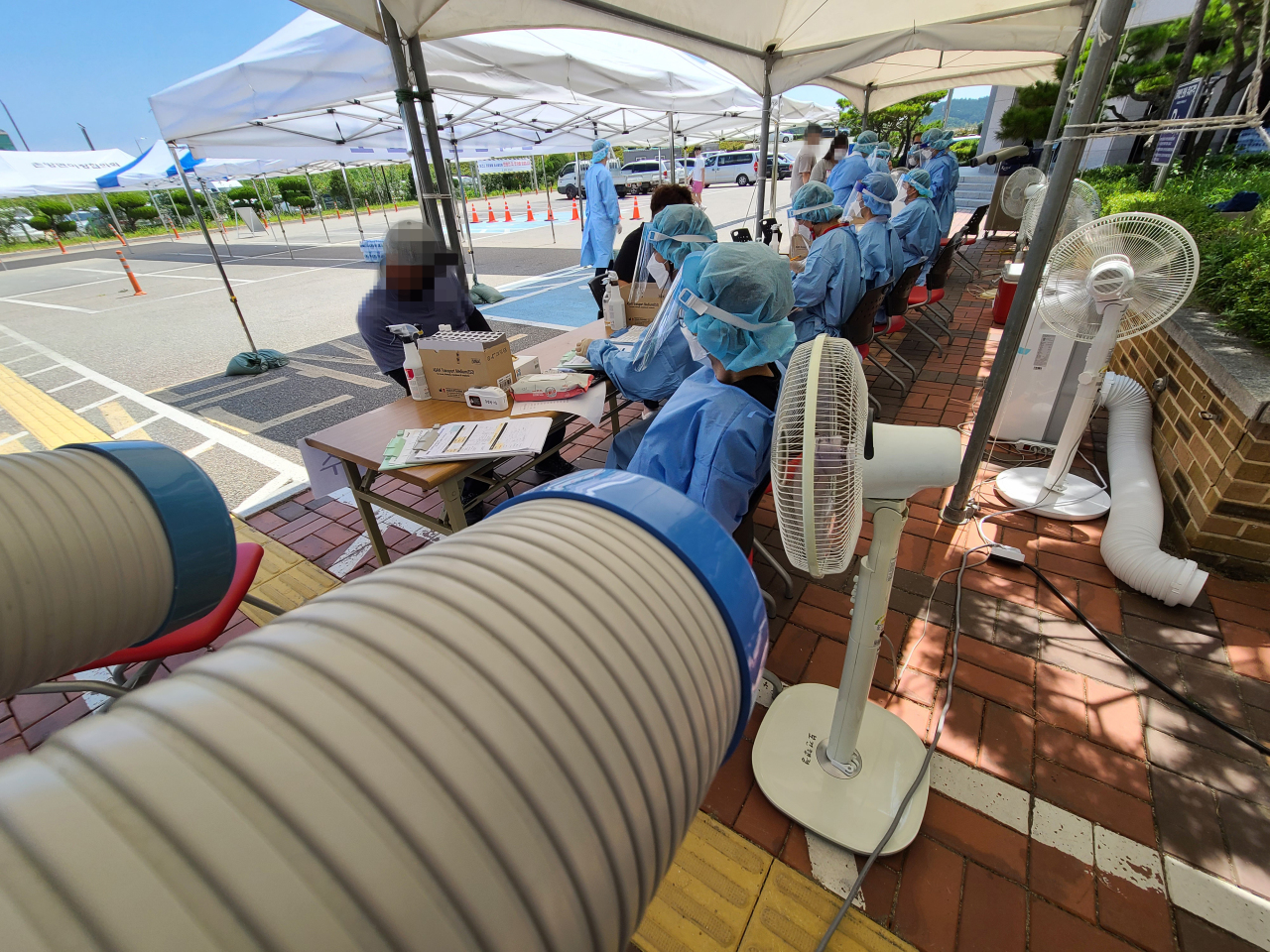 Medical workers administer COVID-19 tests to visitors at a screening facility in Gangwon Province on Sunday. (Yonhap)