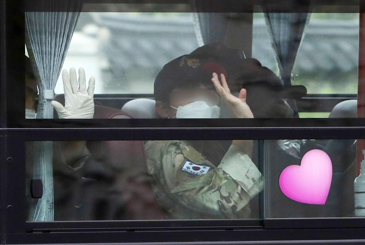 A service member of the Cheonghae Unit is waving a hand to reporters as he heads to a COVID treatment center from Seoul Air Base where the unit was airlifted from Africa on Tuesday. The anti-piracy unit, which had reported a massive COVID outbreak, cut short its mission. (Yonhap)