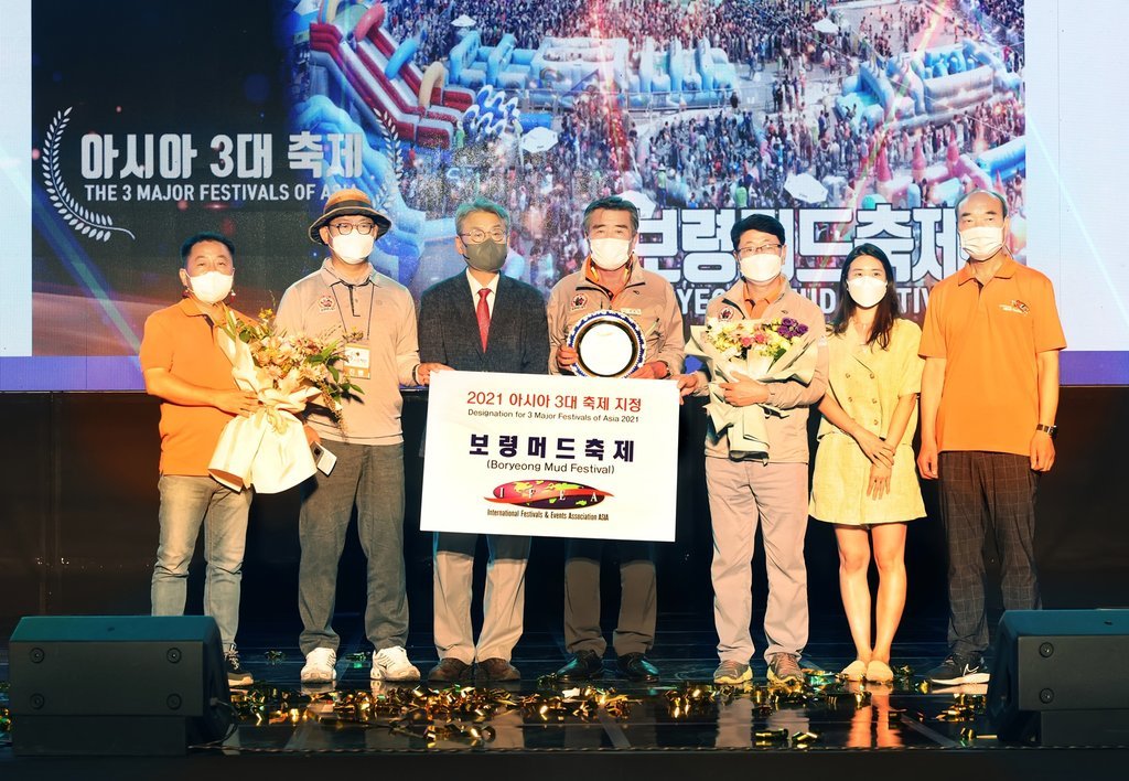 This photo provided by the city government of Boryeong, about 190 kilometers south of Seoul, on Monday, shows its Mayor Kim Dong-il (C) holding a certificate of recognition that Boryeong Mud Festival has been selected as one of the three major festivals of Asia by the International Festivals & Events Association Asia.
