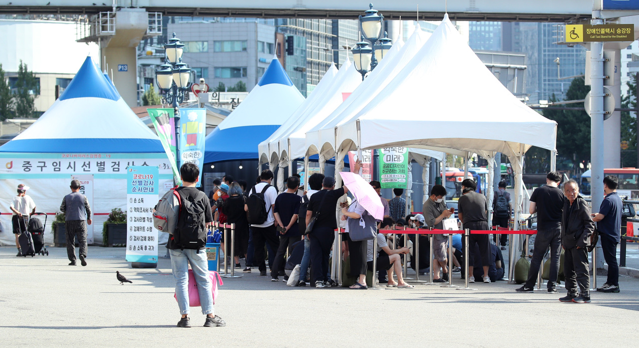 People wait in line to receive COVID-19 tests at a makeshift virus testing clinic in Seoul on Tuesday. (Yonhap)