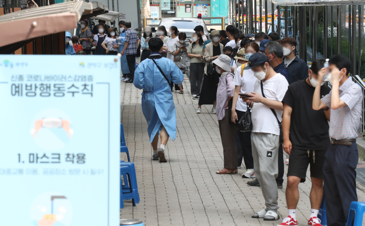 People wait in line to get tested for COVID-19 at a screening center in southern Seoul on Wednesday. (Yonhap)