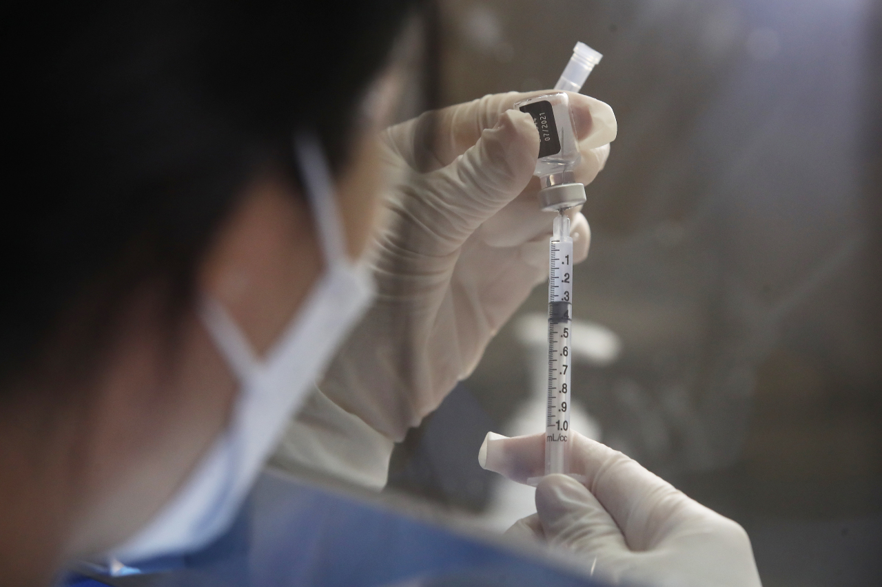 A healthcare worker prepares a COVID-19 vaccine shot at a vaccination center in Seoul. (Yonhap)