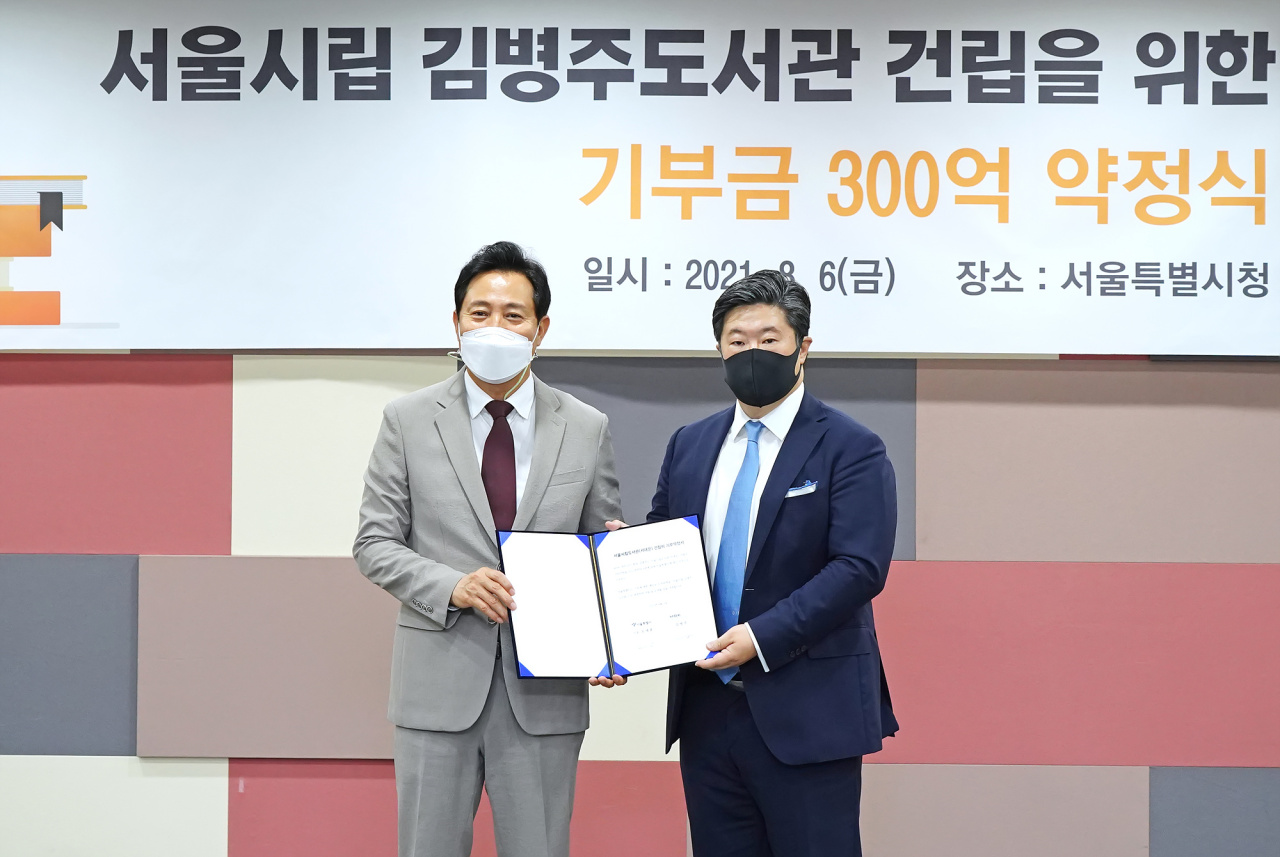 MBK Partners founder Michael Byung-ju Kim (right) and Seoul Mayor Oh Se-hoon pose for a photo to celebrate Kim‘s donation to the Seoul Metropolitan Government at Seoul City Hall Friday. (MBK Partners)