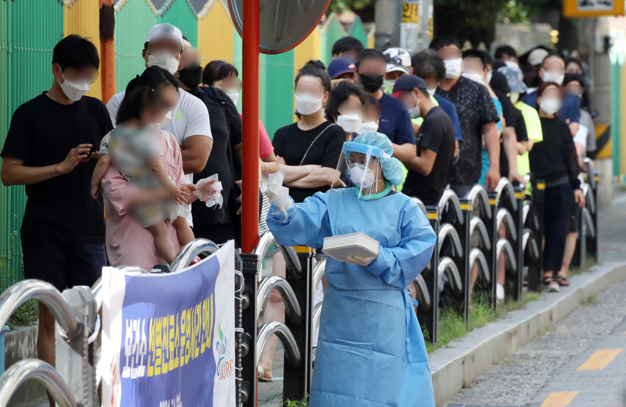 Citizens wait in line for a COVID-19 test at a testing site in Seoul on Tuesday. (Yonhap)