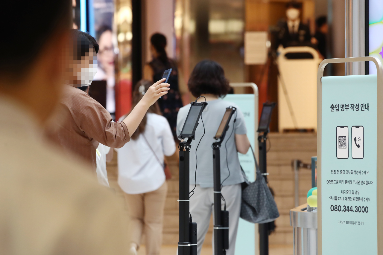 A customer checks in with a temporary QR code embedded in smartphone before entering a department store in Seoul. Korea‘s QR check-in mandates led to wider adoption of online payment and banking. (Yonhap)