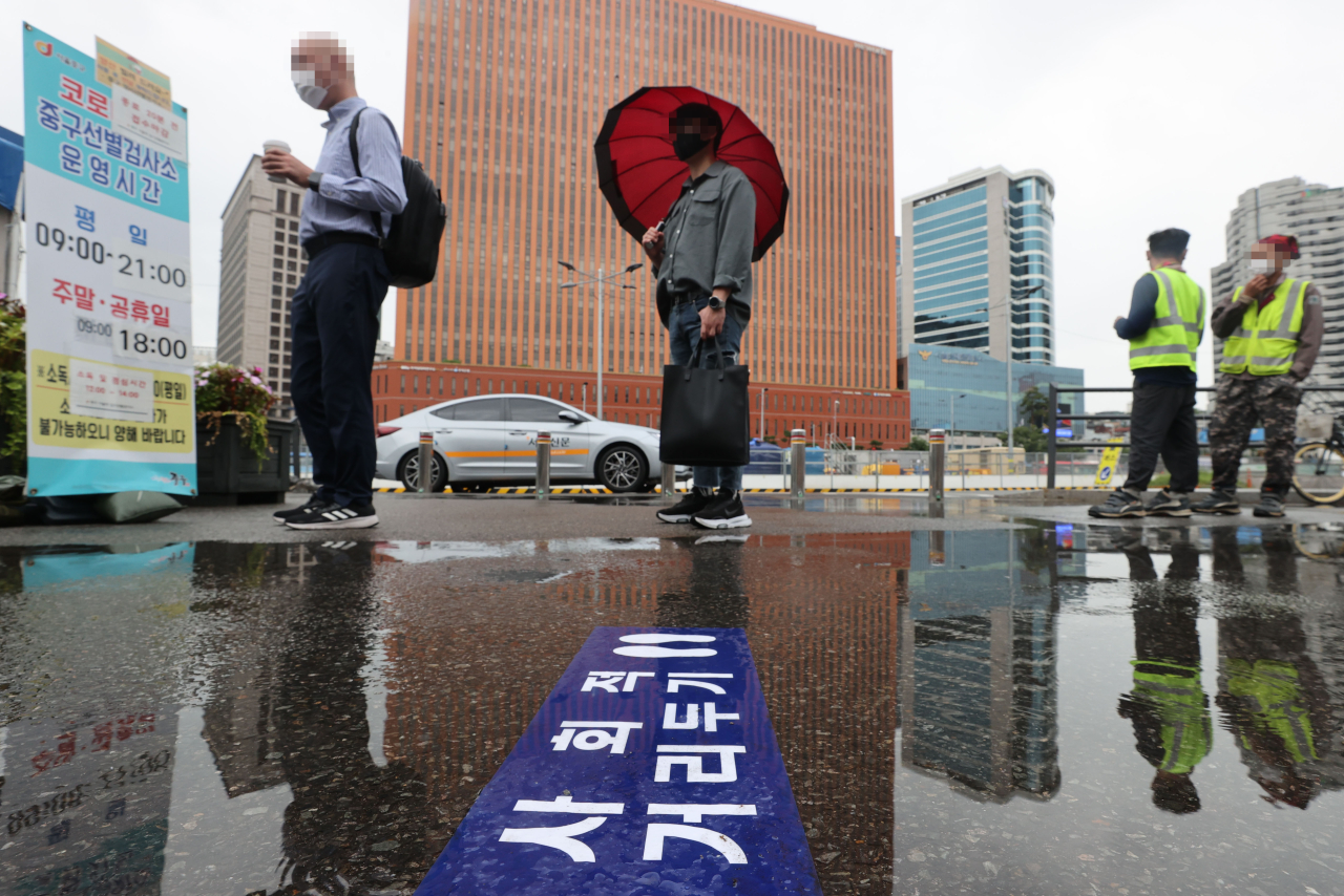 This photo taken on Tuesday, shows people waiting to take a coronavirus test at a makeshift testing center near Seoul Station in central Seoul. (Yonhap)