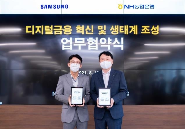 NH NongHyup Bank CEO Kwon Joon-hak, right, and Samsung Electronic Vice President Kang Bong-ku pose for a photo after signing a partnership for digital transformation at the NH Digital Innovation Campus in Seoul on Wednesday. (NH NongHyup Bank)