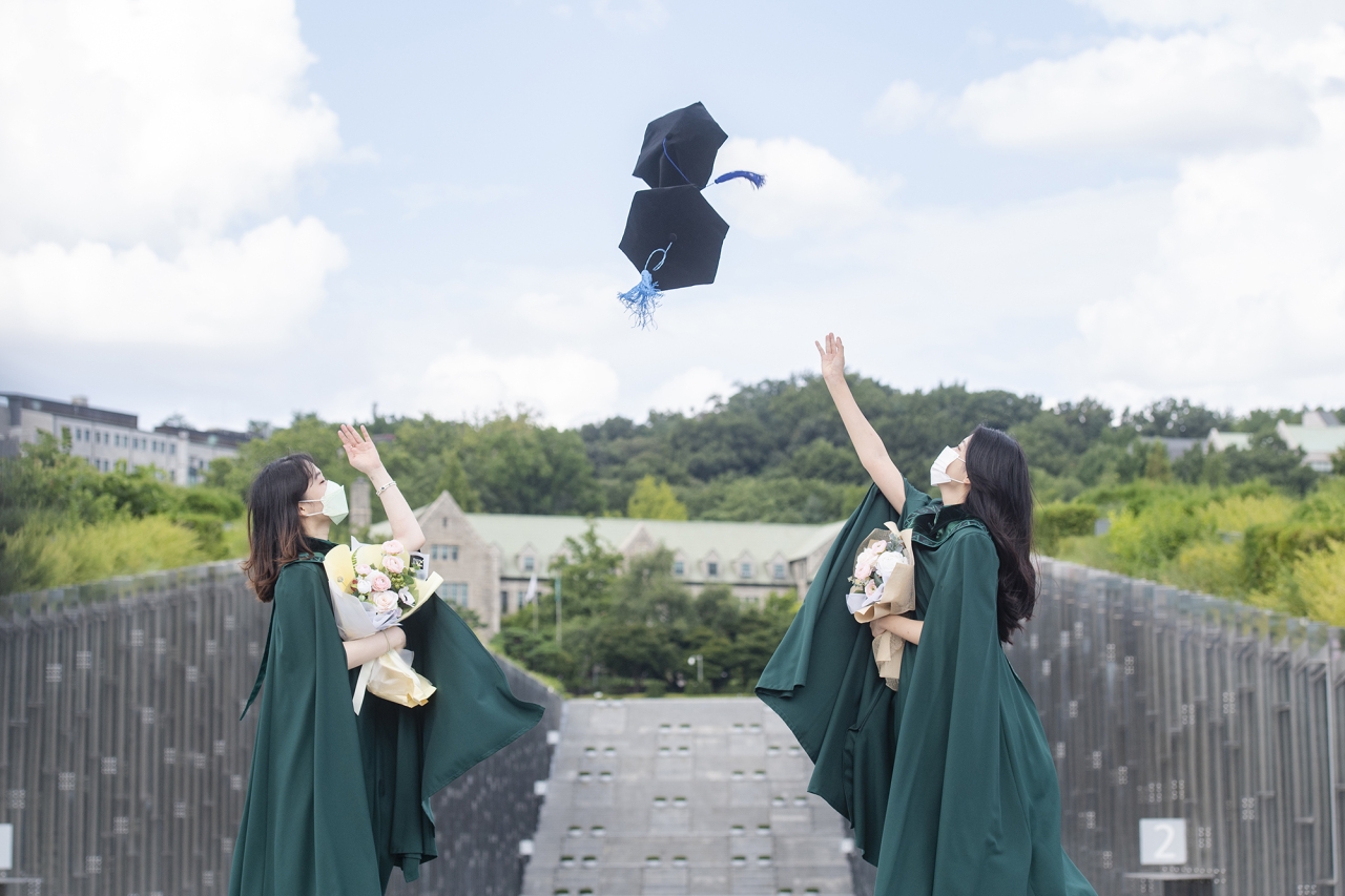 Masked graduates attend the commencement ceremony at Ewha University in Seoul on Friday. (Yonhap)