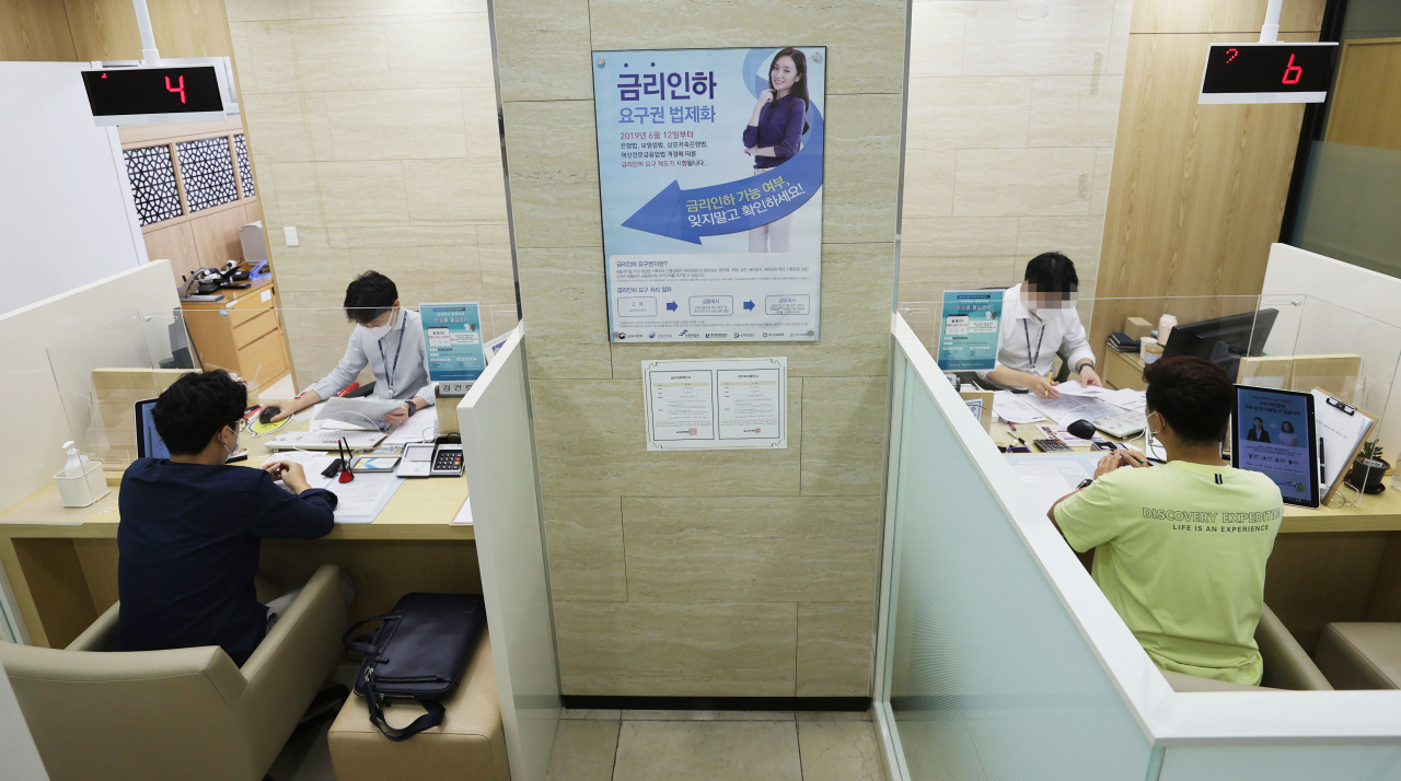 Customers consult bank clerks about loans at a bank in Seoul. (Yonhap)